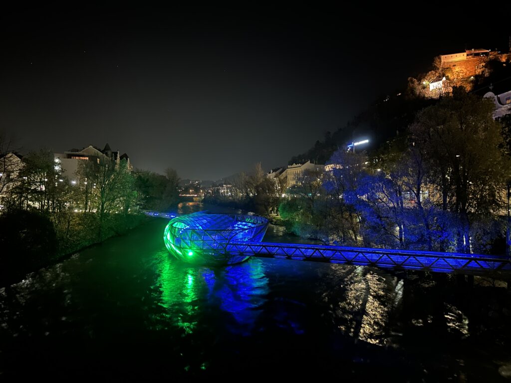 Die Murinsel Graz wird nachts beleuchtet