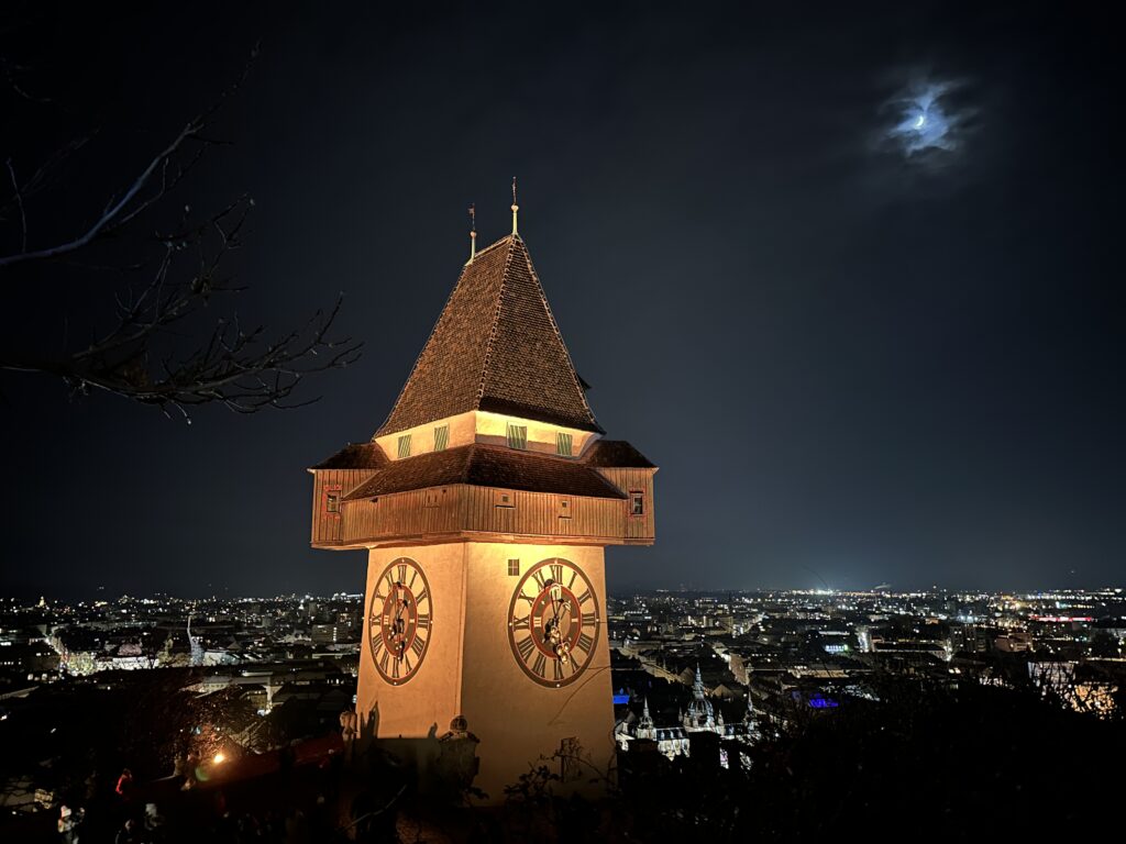 Der Uhrturm Graz wird nachts beleuchtet